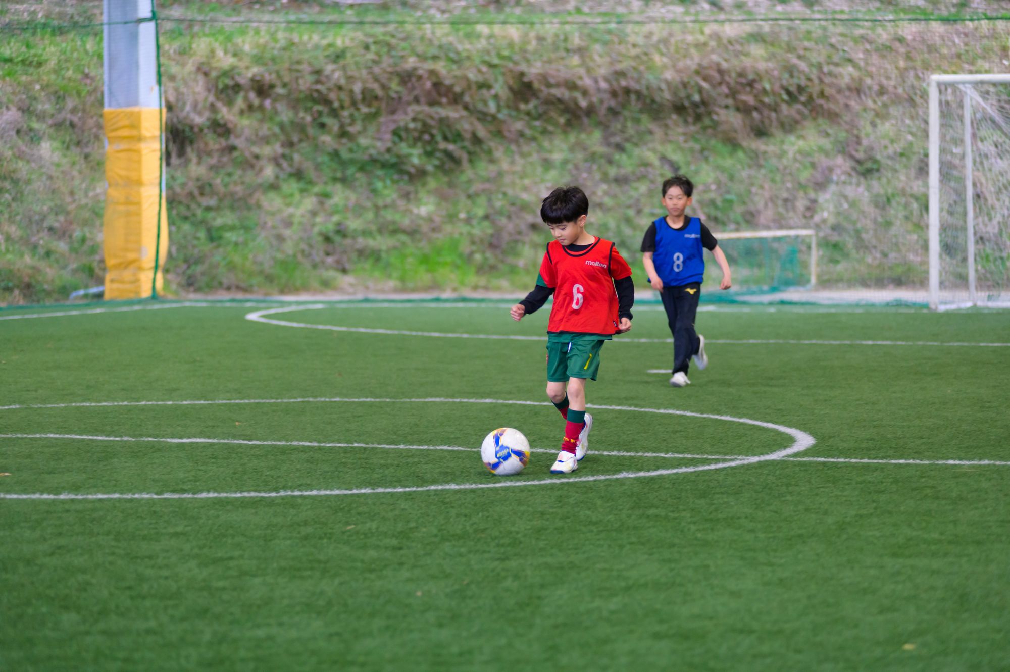 広いコートでボールを追う年中・年長の子どもたち